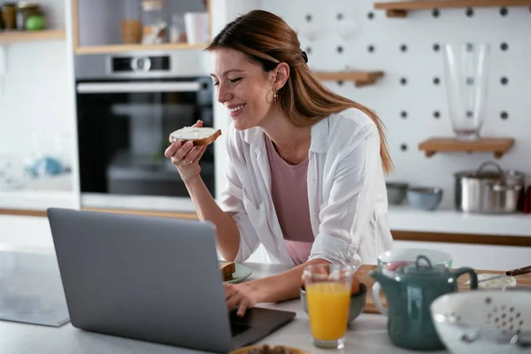 Young Woman Enjoying Her Breakfast While Working Laptop — Stock Photo, Image