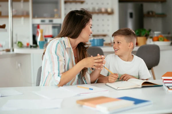 Beautiful young mother helping her kid with homework.