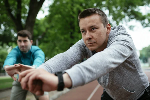 Yarış pistinde egzersiz yapan genç adamlar. Dışarıda antrenman yapan iki genç arkadaş..