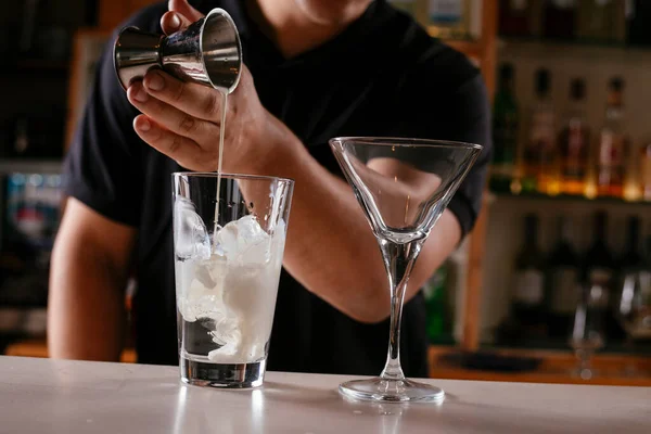 Barman pouring alcoholic drink in to cocktail.