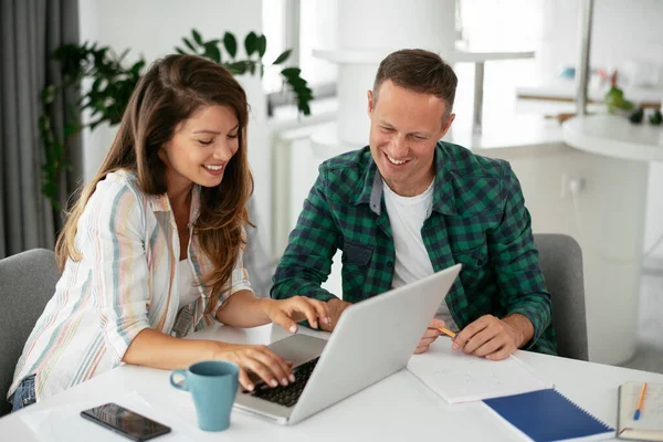 Erkek ve kadın evde dizüstü bilgisayar kullanarak çalışıyor.