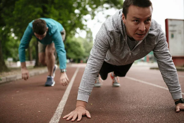 Yarış pistinde egzersiz yapan genç adamlar. Dışarıda antrenman yapan iki genç arkadaş..