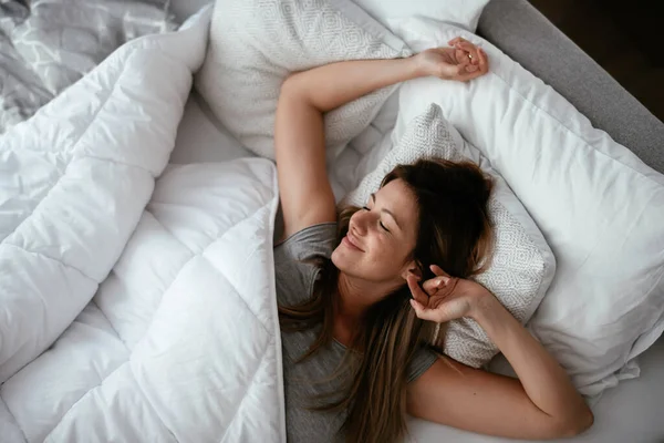 Uyandıktan sonra yatakta gerinen bir kadın. Güzel kız sabah güneşinin tadını çıkarıyor..