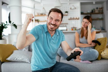 Karı koca oturma odasında joysticklerle oyun oynuyorlar. Sevgili çift evde video oyunu oynuyor..