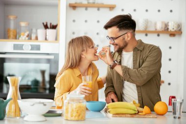 Genç çift evde kahvaltı hazırlıyor. Sevgi dolu çift mutfakta mısır gevreği yiyor..