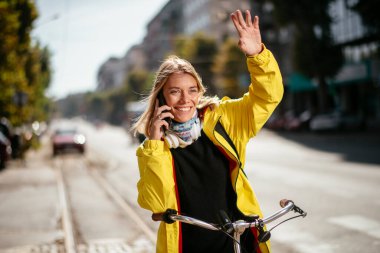 Bisiklet sürerken telefon kullanan genç bir kadın.