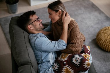 Genç ve sevgi dolu bir çift kanepede dinleniyor. Mutlu çift evde eğleniyor..