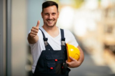 Sokakta sarı kasklı yakışıklı bir işçinin portresi.