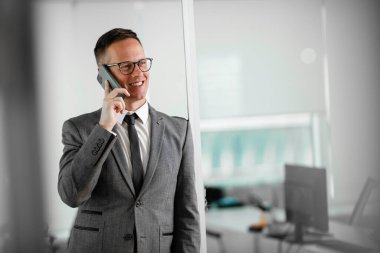 İş adamı telefonda iş konuşuyor. Genç işadamı ofiste telefonda konuşuyor..