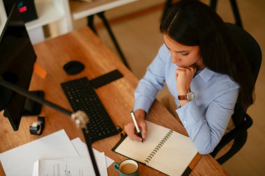 Güzel iş kadını ofisinde oturuyor ve işyerinde çalışıyor. 