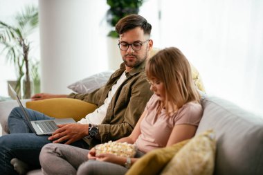 Dizüstü bilgisayarda film izleyen genç bir çift. Sevgili çift evde eğleniyor..