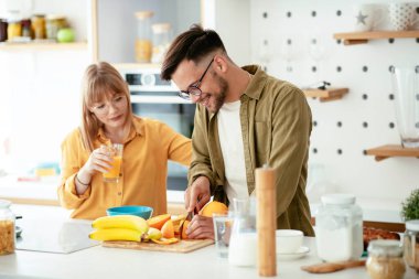 Genç çift evde kahvaltı hazırlıyor. Sevgi dolu çift mutfakta mısır gevreği yiyor..