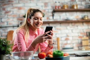 Mutfaktaki kadın. Mutfakta telefon kullanan güzel bir kadın..