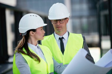 İnşaat alanının yanında durup projeyi tartışan gülümseyen mimarların portresi