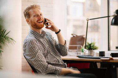 Genç işadamı telefonda konuşuyor.