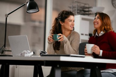 Açık uzay ofisinde konuşan ve gülen mutlu iş kadınları