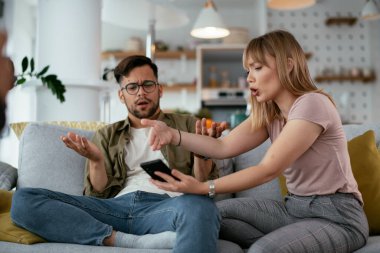 Karı koca kanepede tartışıyor. Kızgın eş kocasına bağırıyor.