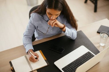 Genç ve güzel iş kadını ofiste notlar alıyor.