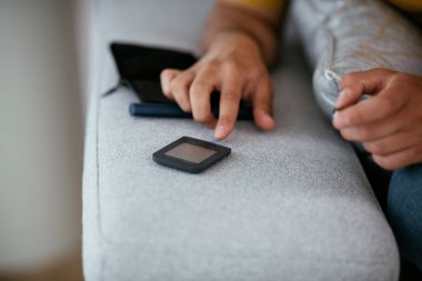 Adam kan şekerini glukometreyle ölçüyor. Genç adam kan şekeri seviyesini ölçüyor..