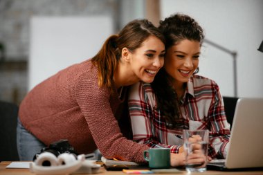 Açık uzay ofisinde konuşan ve gülen mutlu iş kadınları