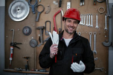 Fabrikadaki genç yakışıklı işçinin portresi. Arka planda aletler var.