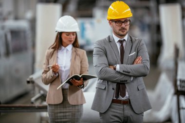 İşadamı ve iş kadını fabrikada iş konuşuyorlar.