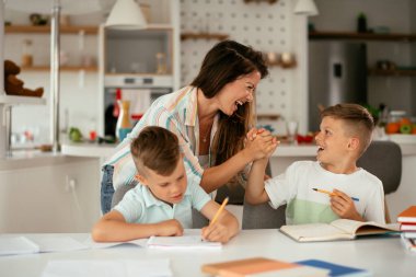 Anne oğullarıyla ödev yapıyor.