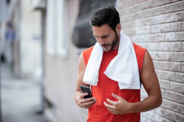 Genç sporcu dışarıda koşuyor. Açık hava eğitiminden sonra yakışıklı bir adam dinleniyor..