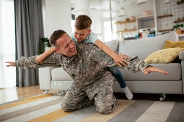 Askerler evlerinde oğluyla oynuyorlar. 