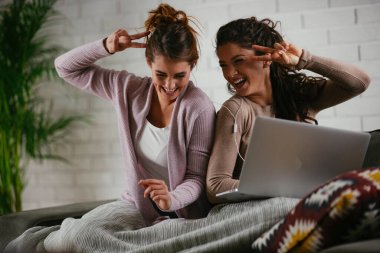 Kız arkadaşlar evde dizüstü bilgisayardan müzik dinlerler. Kızlar apartmanda eğleniyor..