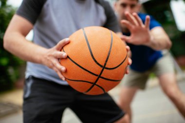 Parkta basketbol oynayan iki genç adam. Arkadaşlar dışarıda dostça bir maç yapıyor.
