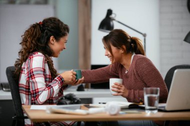 Açık uzay ofisinde konuşan ve gülen mutlu iş kadınları