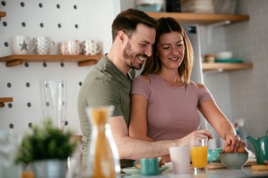 Genç çift evde kahvaltı hazırlıyor. Sevgi dolu çift mutfakta birlikte yemek pişiriyor..