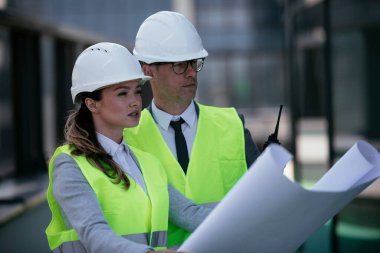 İnşaat alanının yanında durup projeyi tartışan gülümseyen mimarların portresi