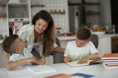 Anne oğullarıyla ödev yapıyor.