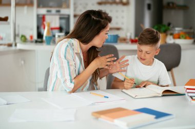 Güzel, genç bir anne çocuğuna ödevlerinde yardım ediyor..