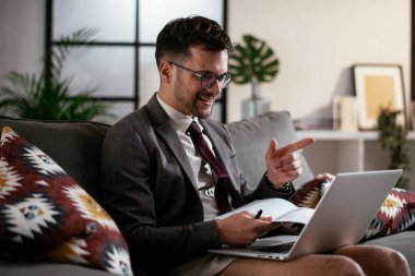 Evde pantolonsuz çalışan bir iş adamı. Genç adam video görüşmesi sırasında bilgisayarı kullanıyor..