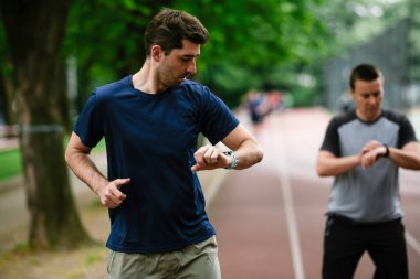Gençler yarış pistinde antrenman yapıyor. İki genç arkadaş atletizm pistinde koşuyor.