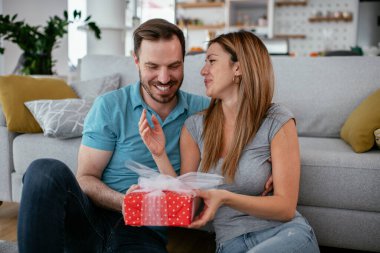 Koca, karısına hediyeyle sürpriz yapıyor. Genç adam karısına hediye kutusu veriyor..