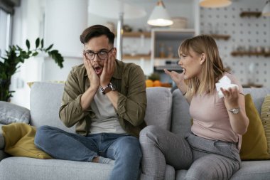 Erkek arkadaşı ve kız arkadaşı kanepede tartışıyor. Kızgın kadın erkek arkadaşına bağırıyor..