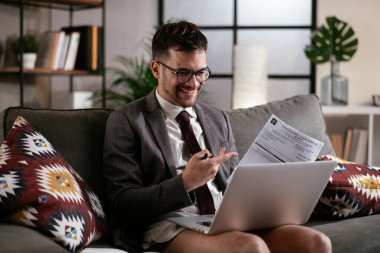 Evde pantolonsuz çalışan bir iş adamı. Genç adam video görüşmesi sırasında bilgisayarı kullanıyor..