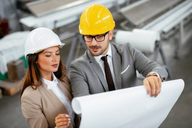 İşadamı ve işkadını fabrikadaki yeni iş projesini tartışıyor