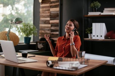 Telefon kullanan bir iş kadını. Ofiste telefonla konuşan mutlu genç bir kadın..