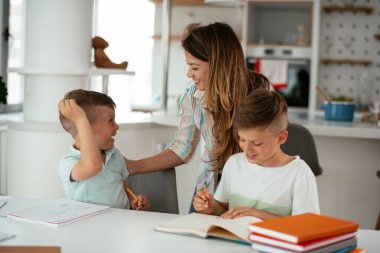 Anne oğullarıyla ödev yapıyor.