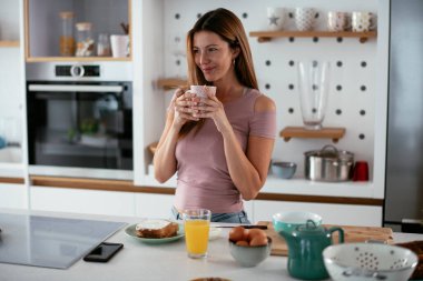 Mutfakta sağlıklı kahvaltı yapan genç bir kadın. Güzel bir kadın evde yemek yiyor..