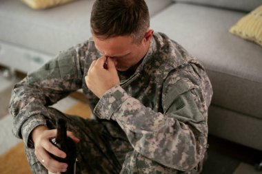 üzgün asker evde alkol içiyor.