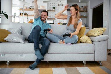 Karı koca oturma odasında joysticklerle oyun oynuyorlar. Sevgili çift evde video oyunu oynuyor..