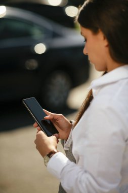 Ofis binasının yanında yürürken elinde cep telefonuyla işe giden güzel bir kadın..