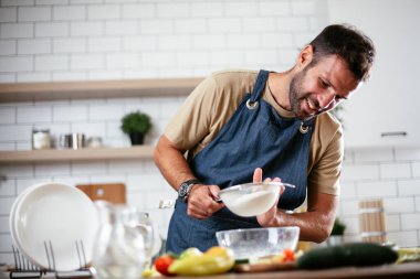 Mutfaktaki yakışıklı adamın portresi. Genç adam evde yemek yaparken eğleniyor..