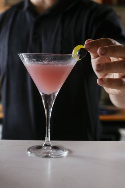 Gece kulübünde kokteyl yapan uzman bir barmen. Barmen barda kırmızı kokteyl hazırlıyor..